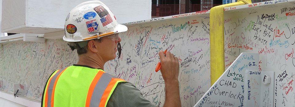 A contractor signs the last steel beam that would be added to the Alfond Center for Health facility