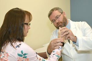 MaineGeneral Orthopaedics hand surgeon John Thaller, MD examines a patient's wrist injury